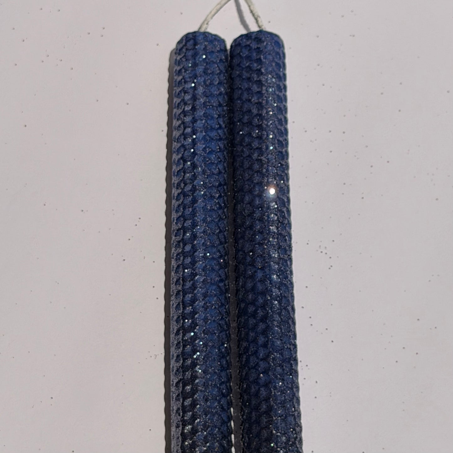 Illuminate your space with the regal beauty of our Black Sapphire Specialty Candle. Hand-rolled from our Bright Blue beeswax, each candle is adorned with a dusting of graphite metallic glitter, allowing the deep sapphire glow to shine through. With every flicker, it captures a bold, captivating elegance, perfect for special occasions or a touch of nighttime charm.