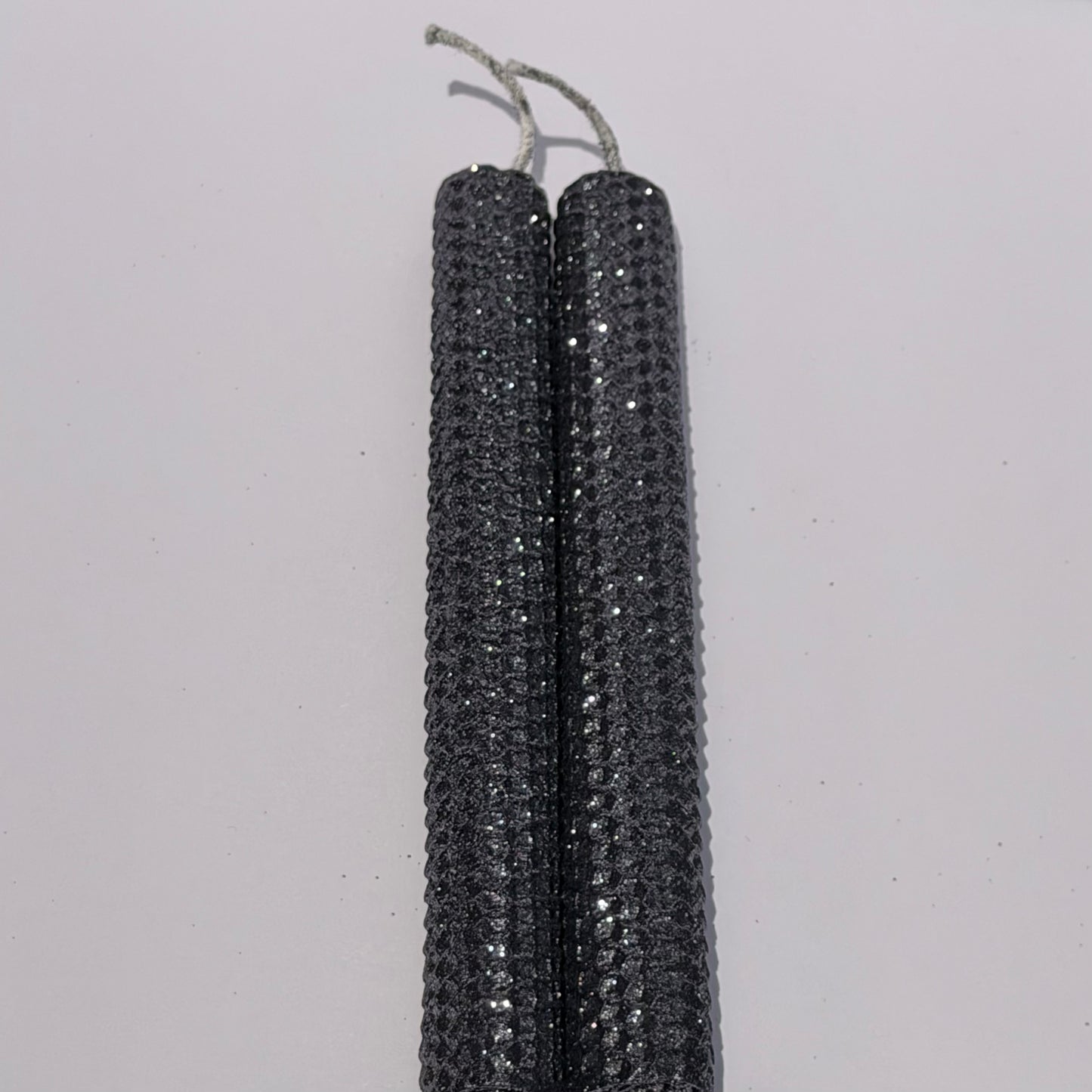 Add a touch of modern elegance with our Graphite Metallic Glitter Taper Candles. Inspired by the sleek depth of pencil lead, these candles are a rich graphite gray, coated in a dazzling metallic glitter that catches the light and enhances every subtle curve. Perfect for adding a refined, luminous accent to any dinner or special event.