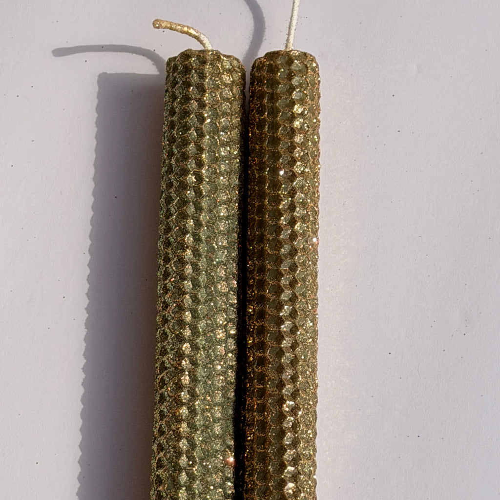 Embrace the essence of autumn with our Fall Brass Specialty Candle. Hand-rolled from olive green beeswax, this candle is crowned with a fine dusting of brass metallic glitter, letting the rich green glow softly beneath. Perfect for adding a subtle shimmer and a warm, seasonal charm to any event or gathering.