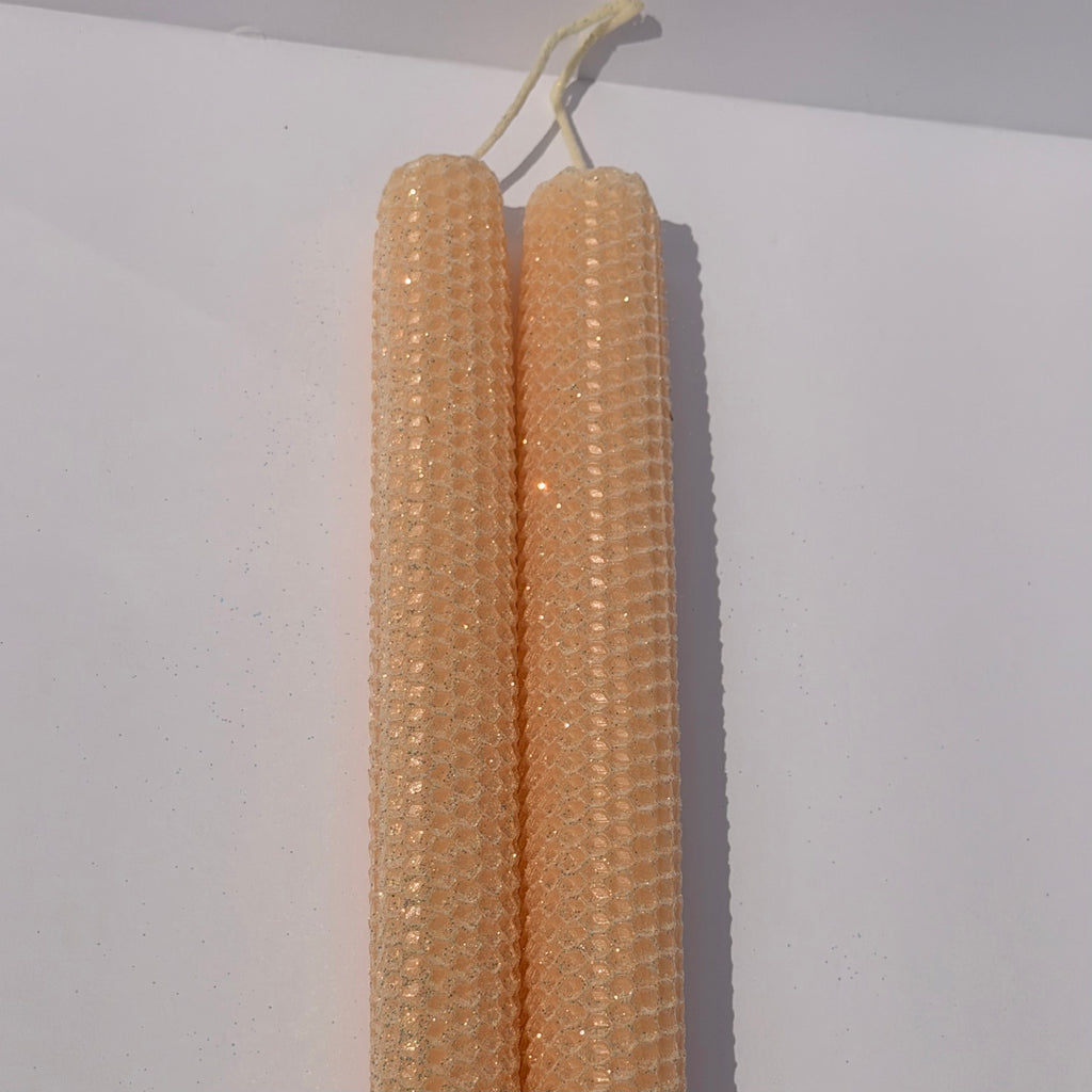 Our Champagne Limited Edition is a luminous celebration of elegance. Hand-rolled from pure beeswax, it radiates a creamy champagne hue with a whisper of pale pink. Delicately dusted in our classic iridescent glitter, it catches the light with a subtle gold undertone, making each candle a radiant, one-of-a-kind treasure