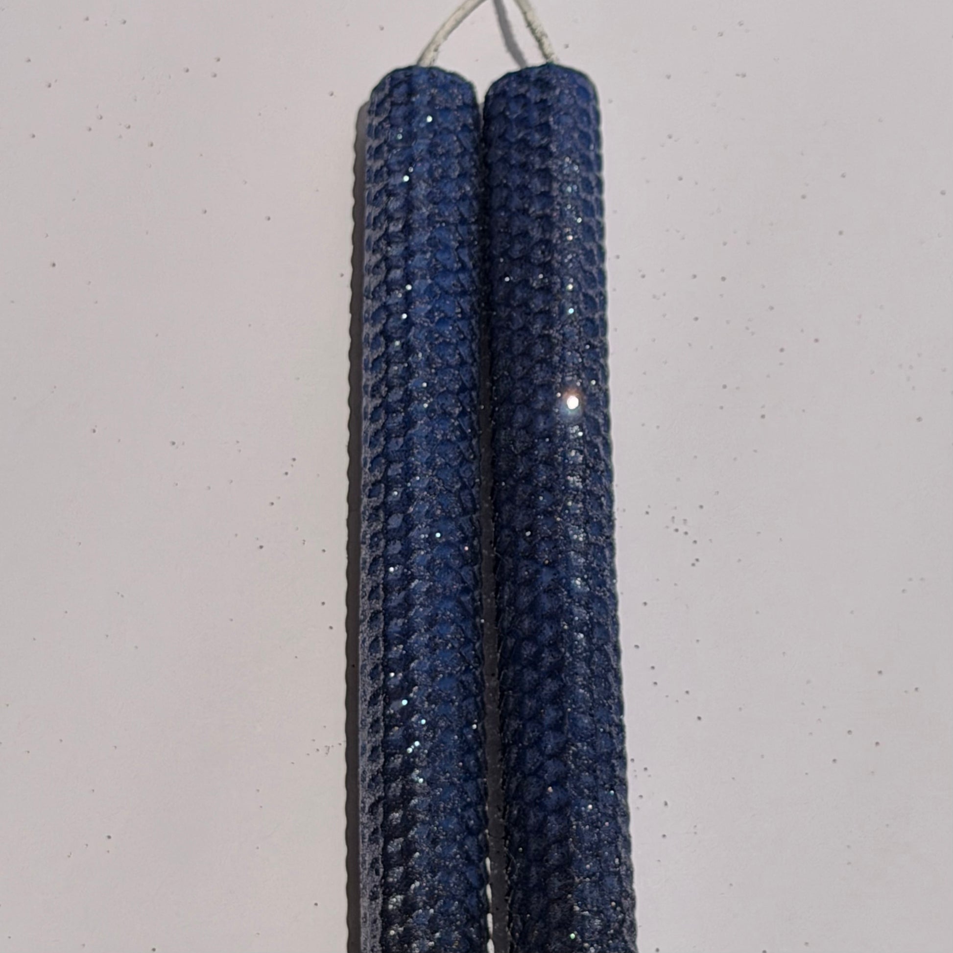 Illuminate your space with the regal beauty of our Black Sapphire Specialty Candle. Hand-rolled from our Bright Blue beeswax, each candle is adorned with a dusting of graphite metallic glitter, allowing the deep sapphire glow to shine through. With every flicker, it captures a bold, captivating elegance, perfect for special occasions or a touch of nighttime charm.