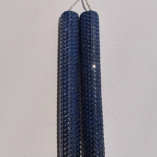 Illuminate your space with the regal beauty of our Black Sapphire Specialty Candle. Hand-rolled from our Bright Blue beeswax, each candle is adorned with a dusting of graphite metallic glitter, allowing the deep sapphire glow to shine through. With every flicker, it captures a bold, captivating elegance, perfect for special occasions or a touch of nighttime charm.