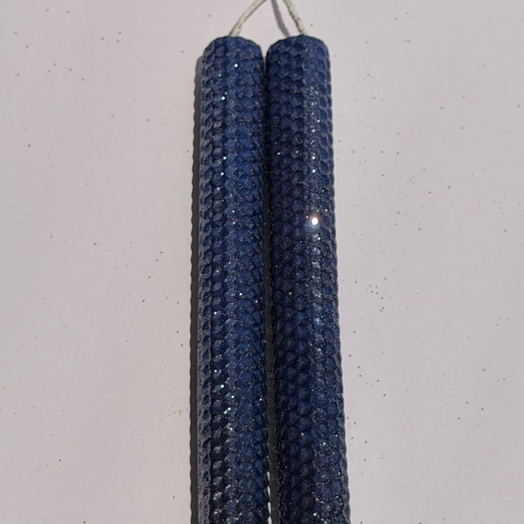 Illuminate your space with the regal beauty of our Black Sapphire Specialty Candle. Hand-rolled from our Bright Blue beeswax, each candle is adorned with a dusting of graphite metallic glitter, allowing the deep sapphire glow to shine through. With every flicker, it captures a bold, captivating elegance, perfect for special occasions or a touch of nighttime charm.