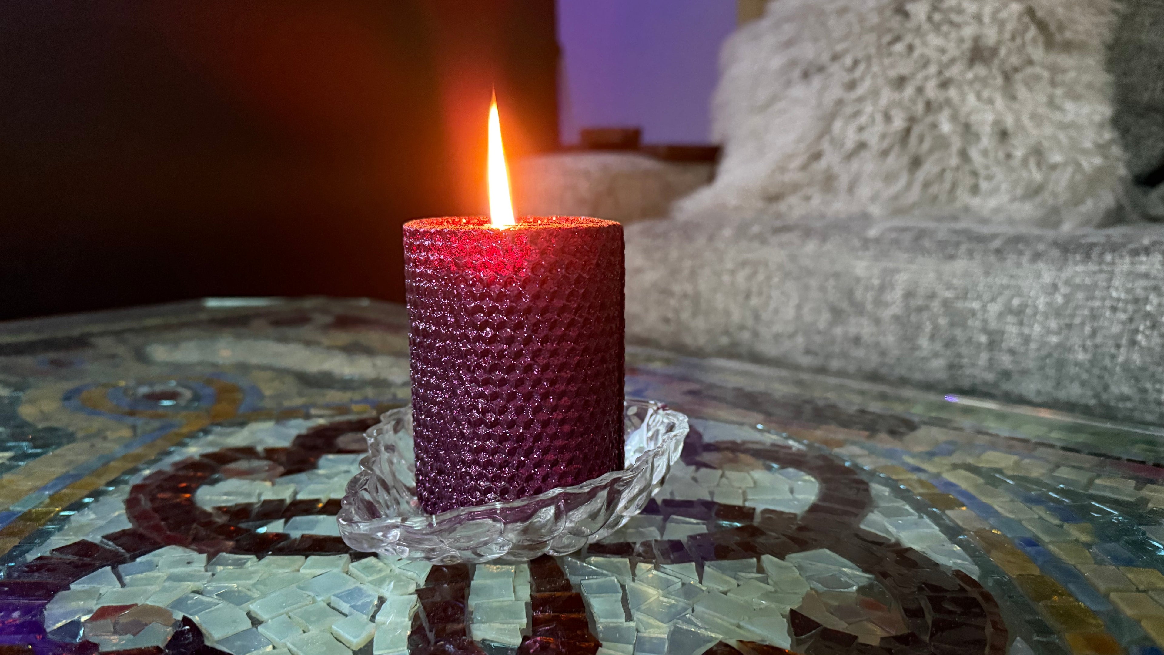 Purple candle on a decorative glass table with a blurred background